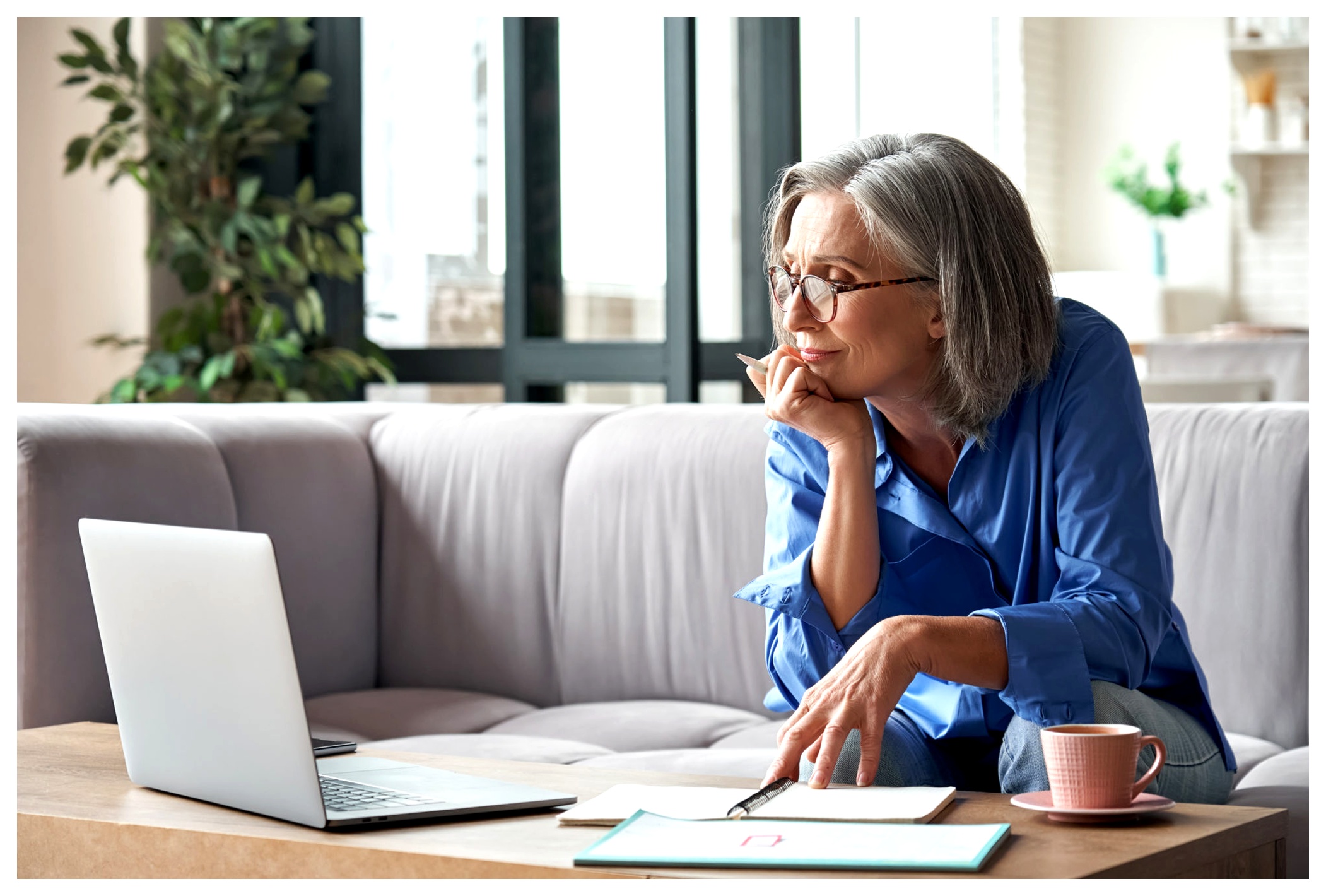 a woman reading on her laptop and making notes