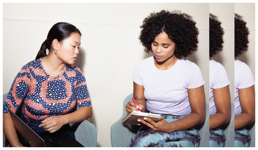 2 women chatting and taking notes
